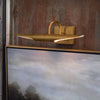Radford Picture Light - Small Natural Brass styled above a gold framed photo. Styled view.