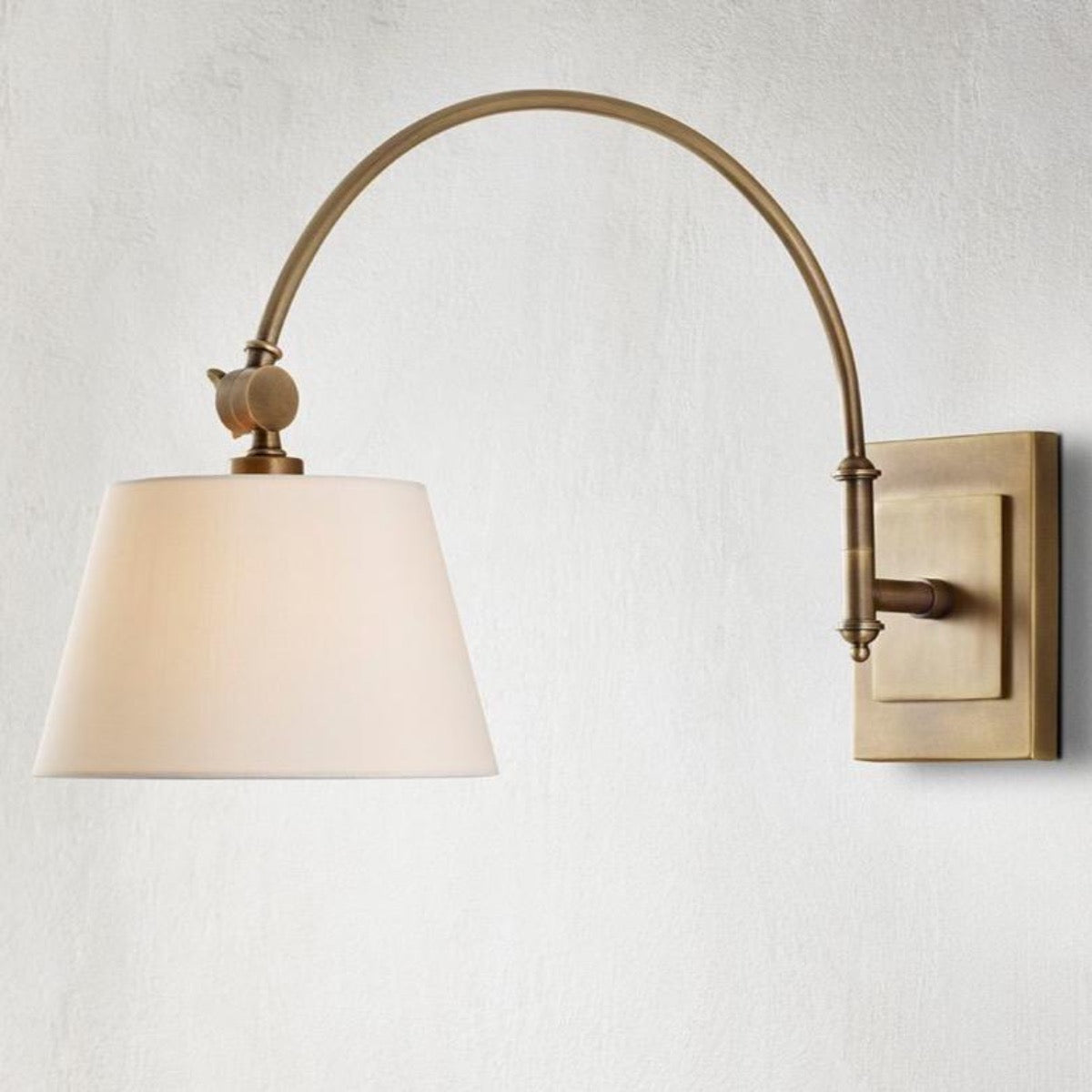 Rennie Swing-Arm Wall Sconce styled on a grey wall. Styled view.