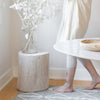 Rosalie Round Stump styled with white flowers on a grey rug. Styled view.