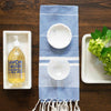 Round Marble Scalloped Bowl styled with clothes and soap on a wood table. Styled view.