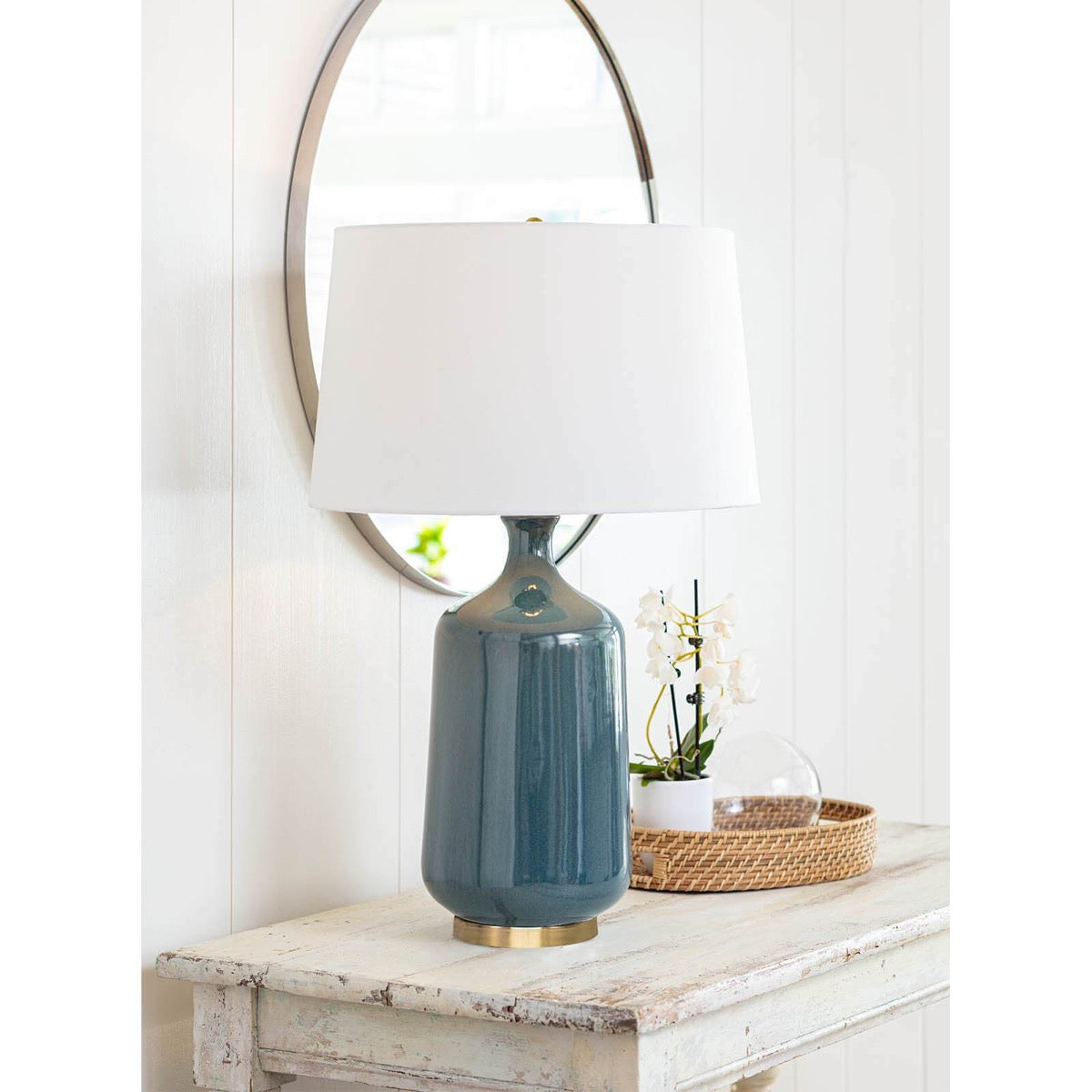 Rowen Mirror styled above a distressed table with blue lamp and decor. Styled view.