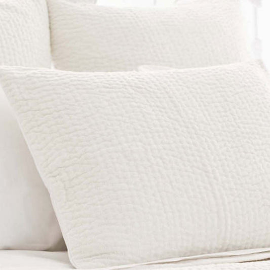 Seychelles Dove White Quilted Sham styled with white sheets. Styled view.