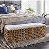Sira Rattan Bench styled at the end of a blue and white bed with a brown rug. Styled view.