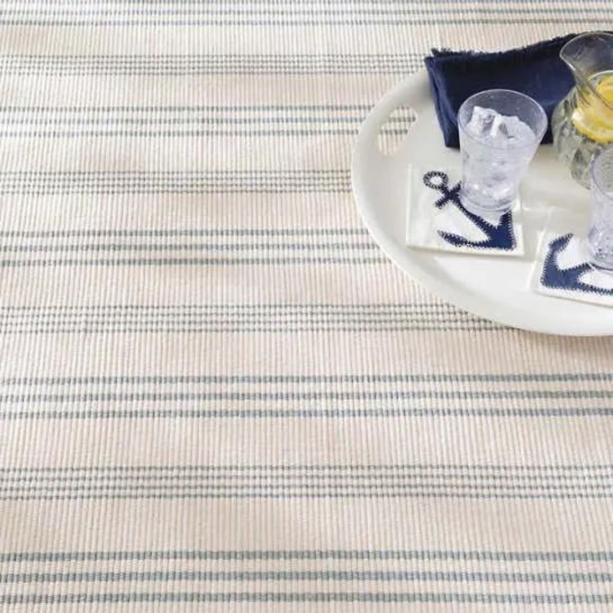 Swedish Stripe Woven Cotton Rug styled under a white tray with navy accents. Styled view.