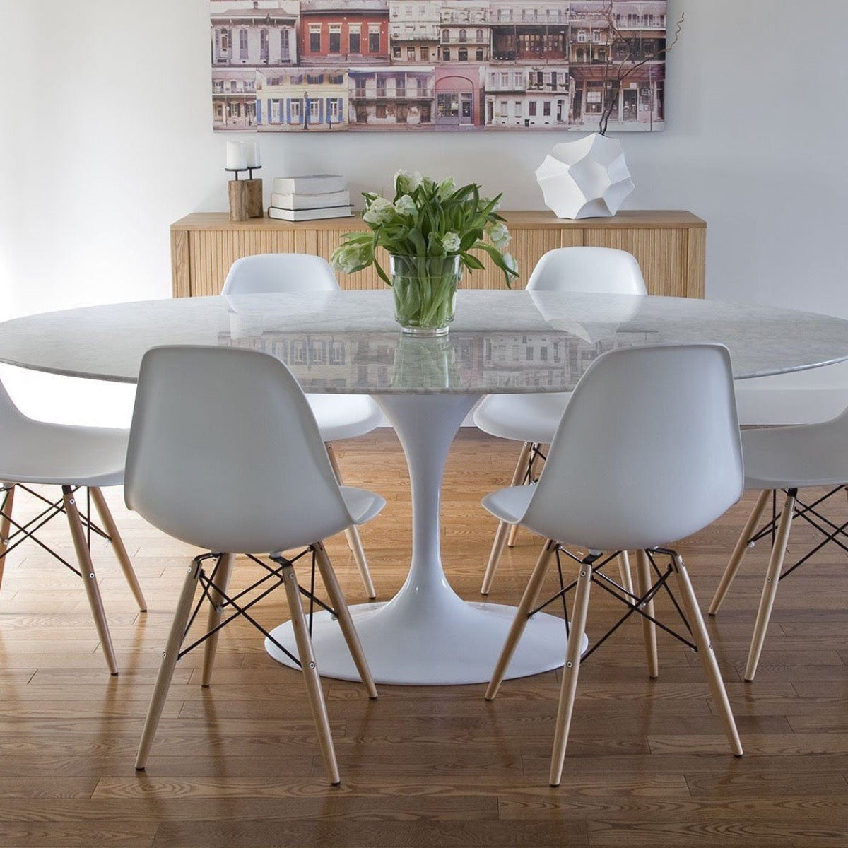 Trumpet Dining Table Oval with Marble Top - Large styled with white chairs and wood console table on light wood floors. Styled view.