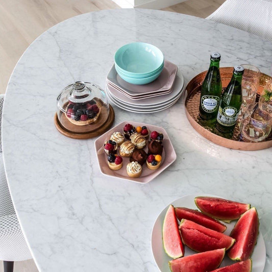 Trumpet Dining Table Oval with Marble Top - Large styled with plates, fruits and desserts. Styled view.