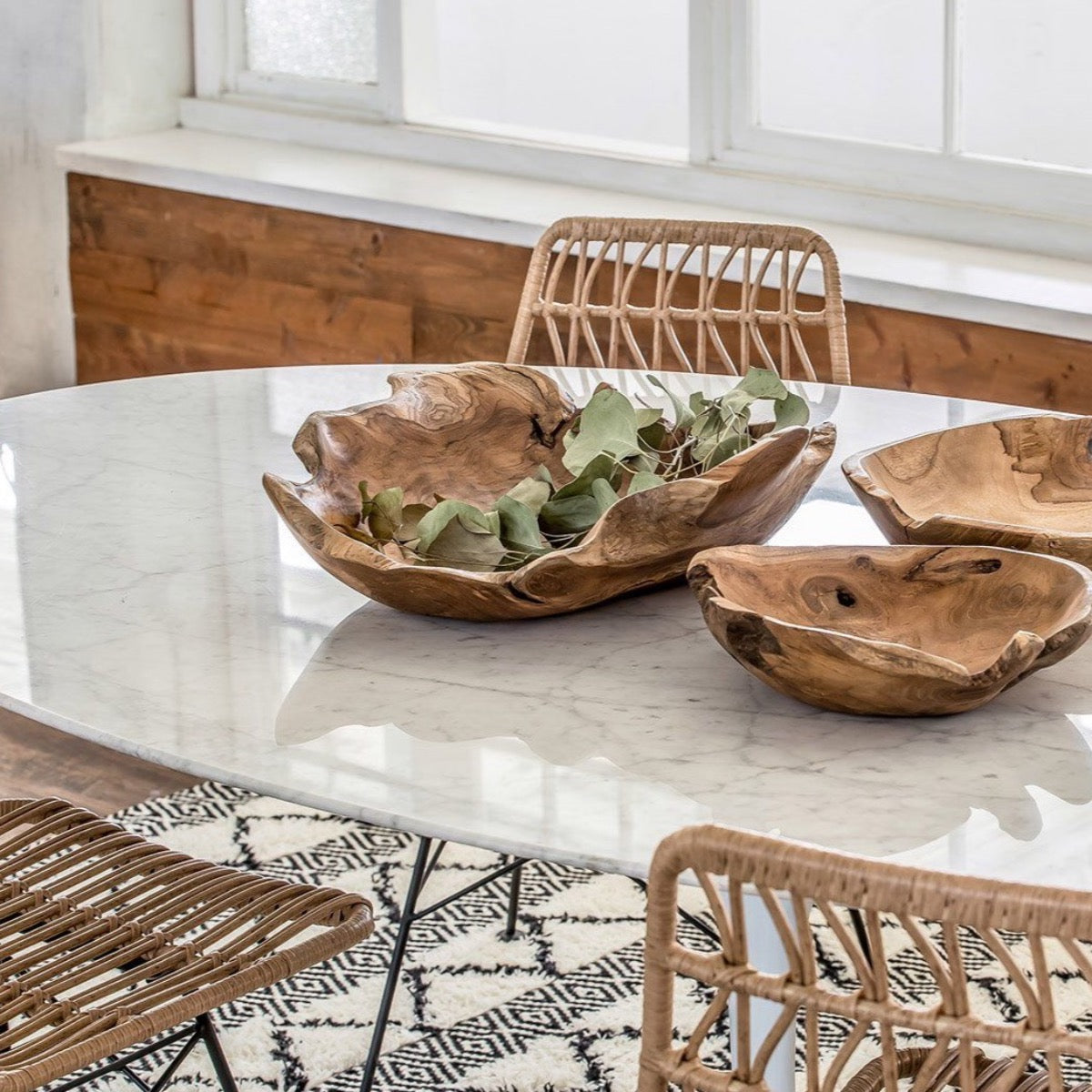 Trumpet Dining Table Oval with Marble Top - Large styled with wood bowls and wicker chairs. Styled view.