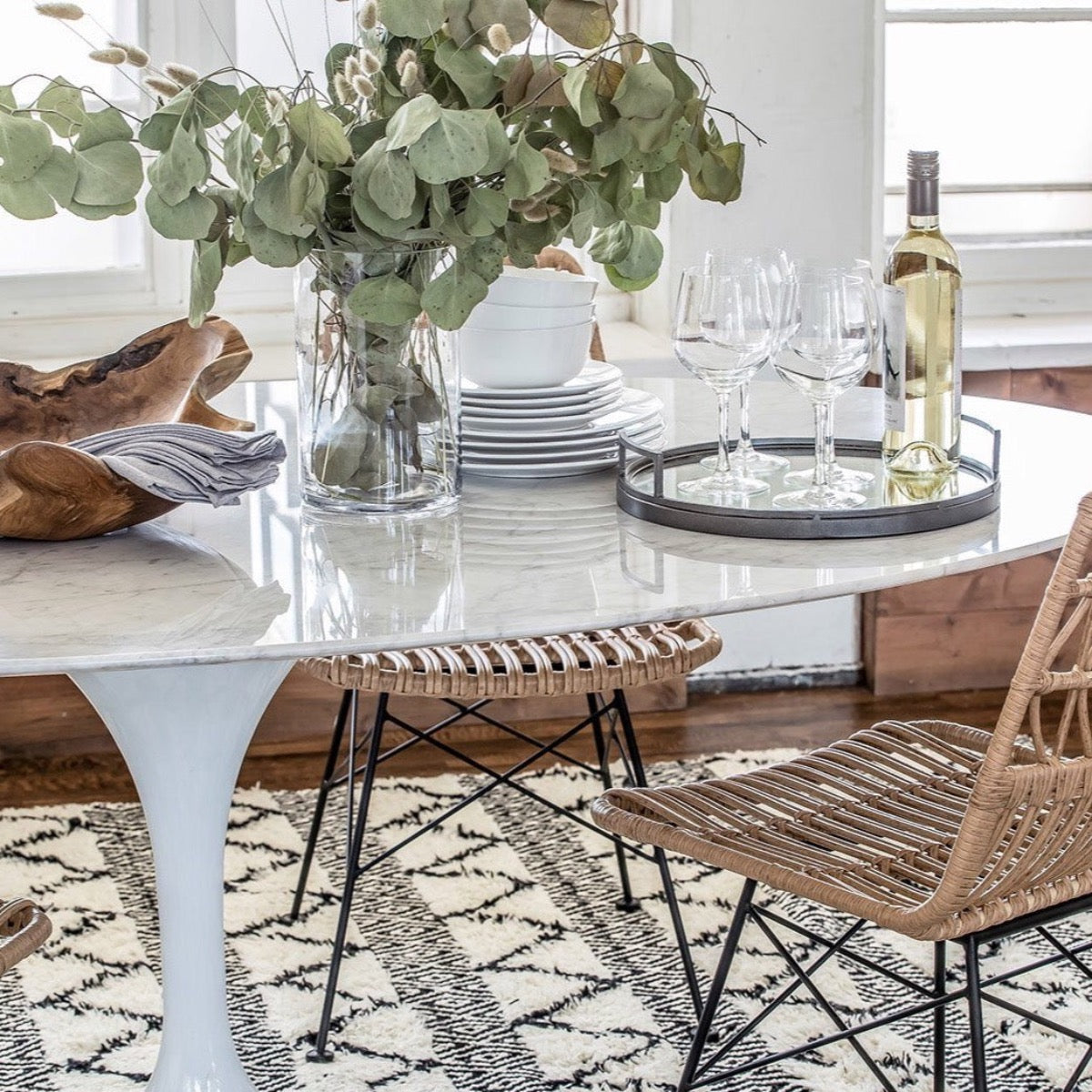 Trumpet Dining Table Oval with Marble Top - Small styled with wicker chairs, serveware and greenery centrepiece. Styled view.