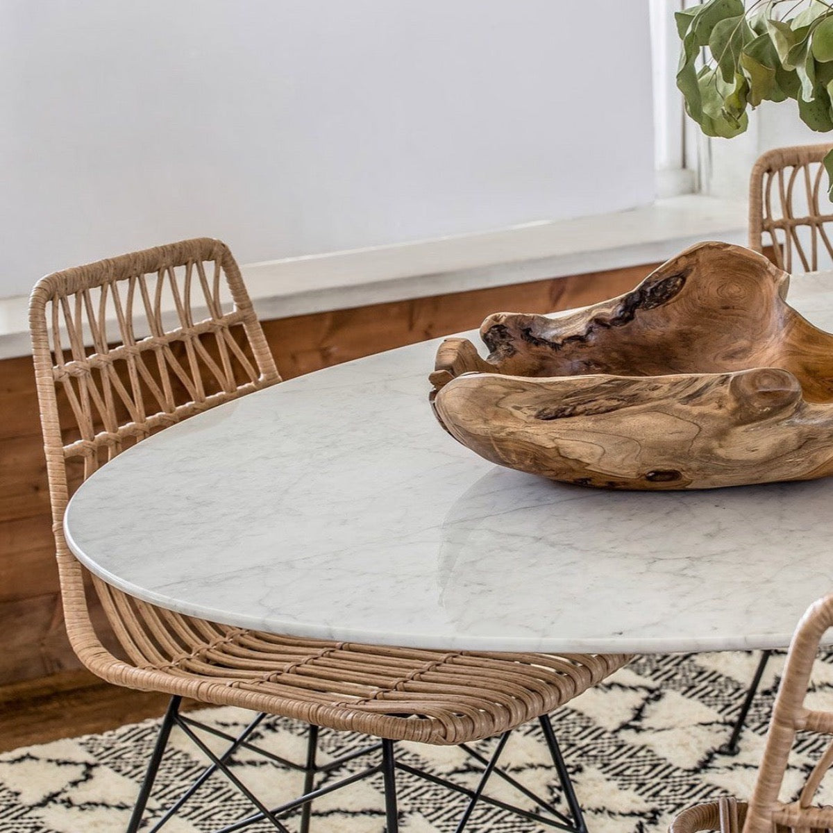 Trumpet Dining Table Oval with Marble Top - Small styled with wood bowl and chairs on a fluffy rug. Styled view.