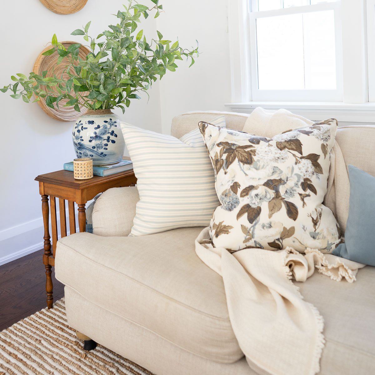 Twiggy Natural Woven Wool/Jute Rug styled under a neutral sofa. Styled view.
