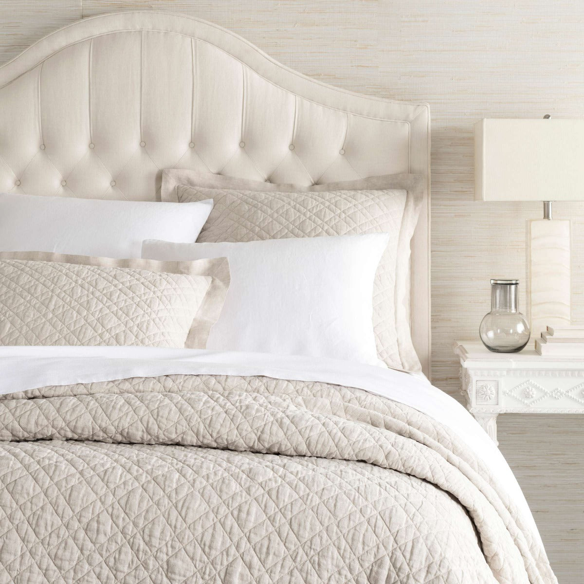 Washed Linen Natural Quilt styled with white sheets. Styled view.