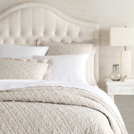 Washed Linen Natural Quilt styled with white sheets. Styled view.