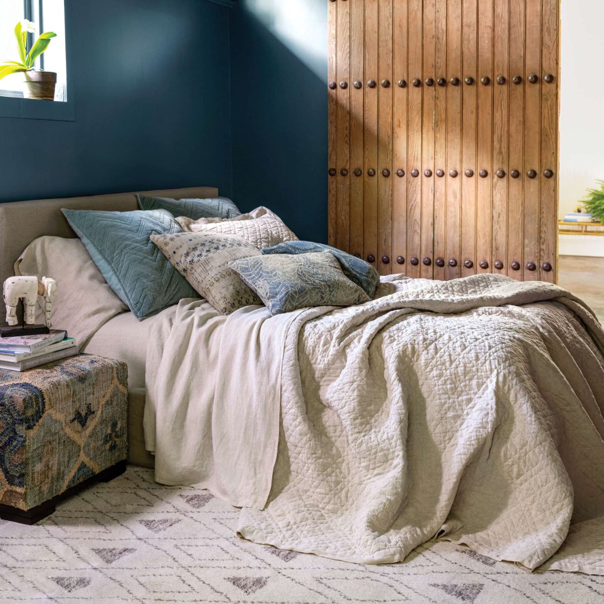 Washed Linen Natural Quilt styled with neutral bedding in a navy room. Styled view.