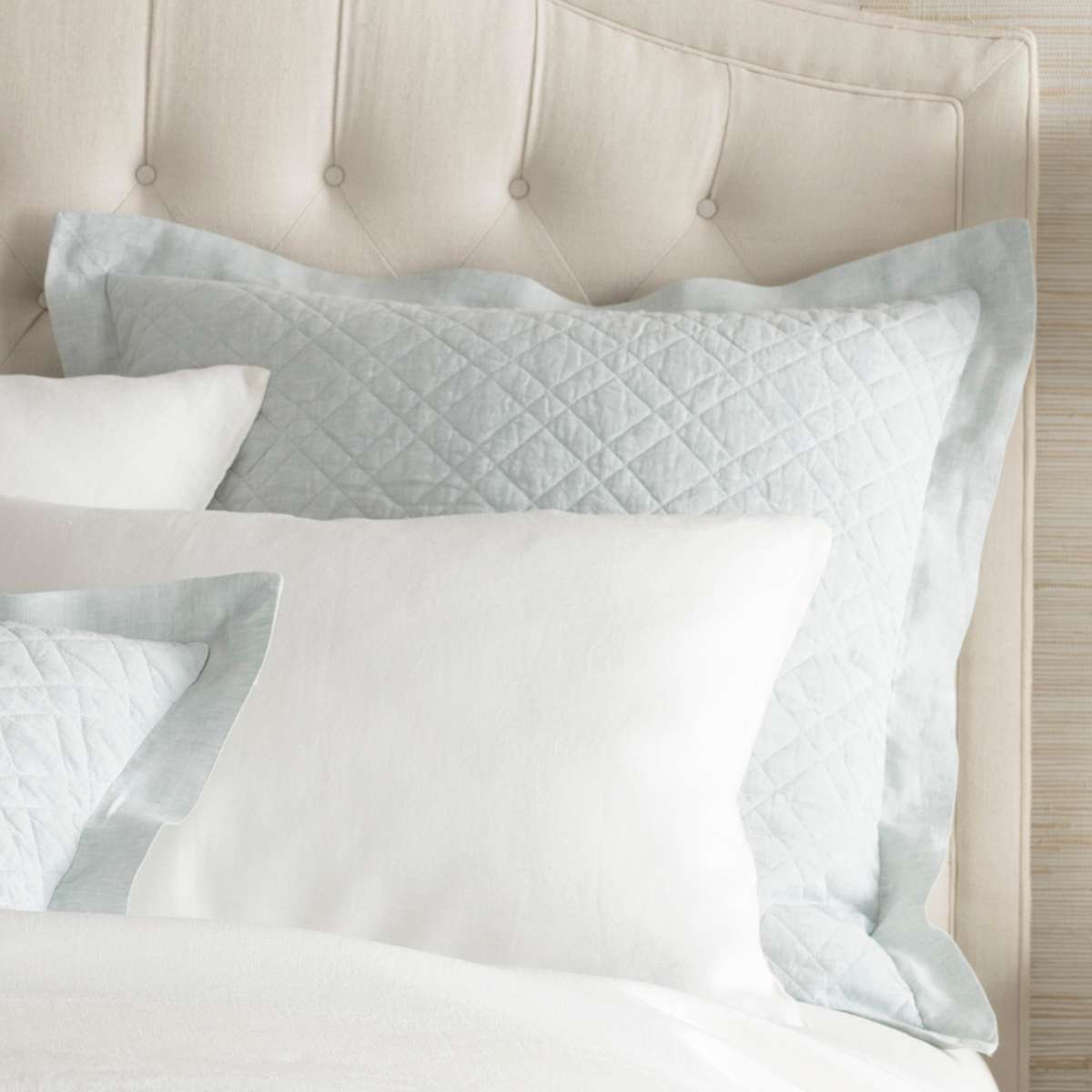 Washed Linen Sky Quilted Sham styled with white sheets. Styled view.