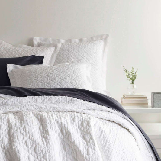 Washed Linen White Quilt styled with navy sheets. Styled view.