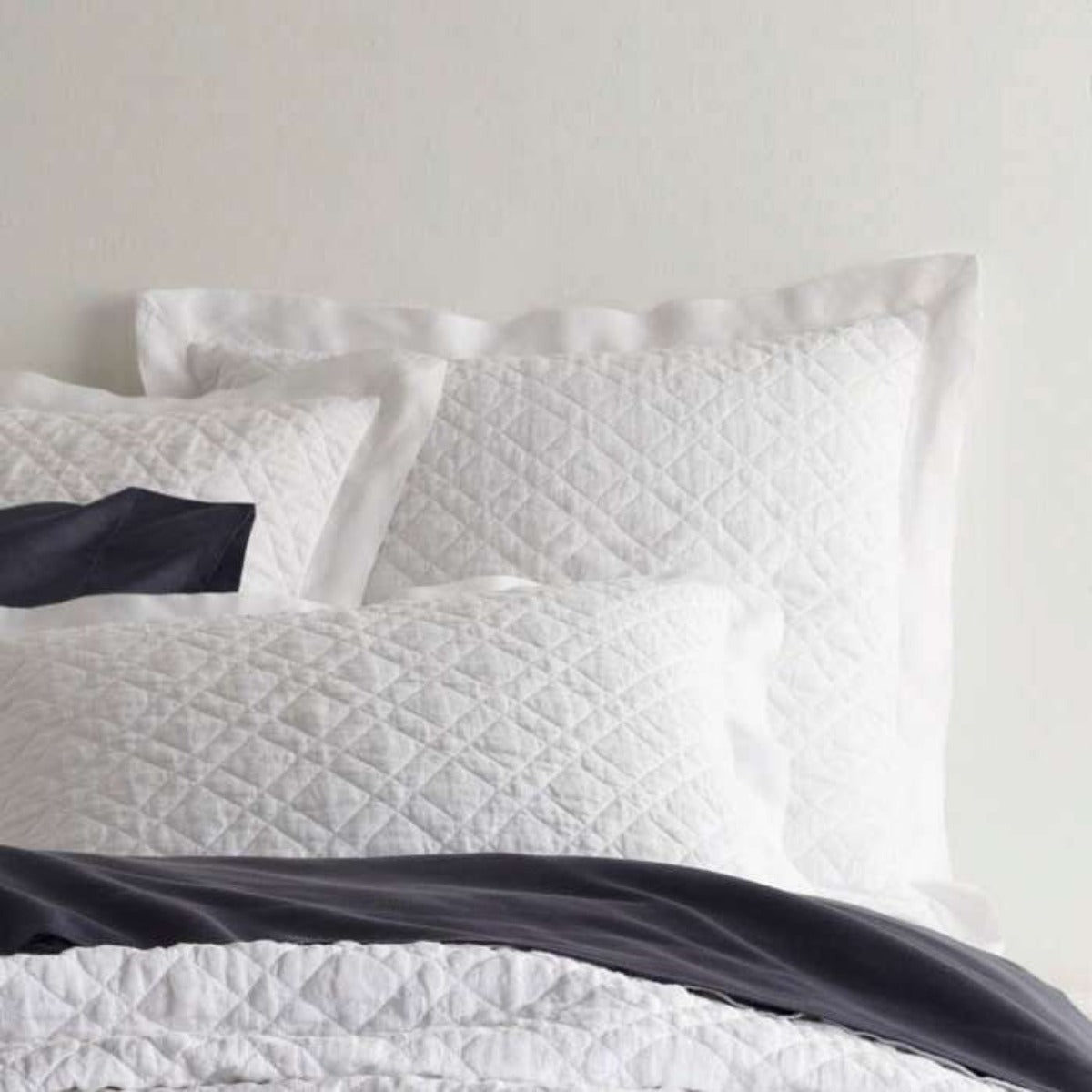 Washed Linen White Quilted Sham styled with navy sheets. Styled view.