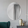 Zara Mirror hanging on a grey wall behind a green sofa. Styled view.