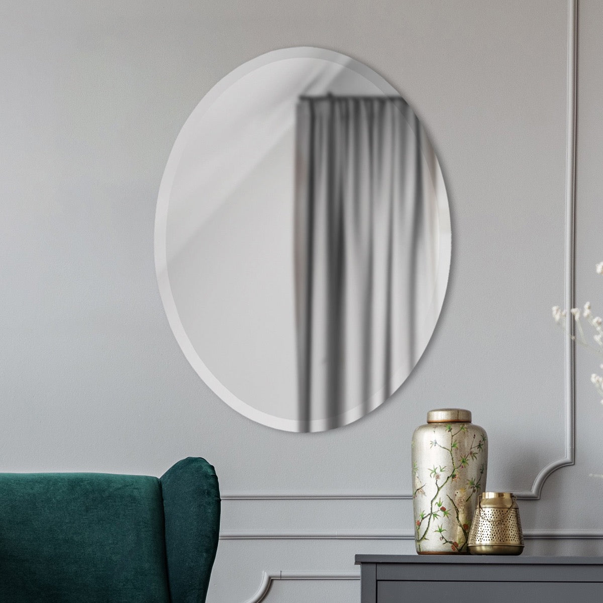 Zara Mirror hanging on a grey wall behind a green sofa. Styled view.