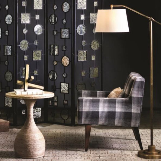 Albany Floor Lamp styled in a dark room with a plaid accent chair. Styled view.