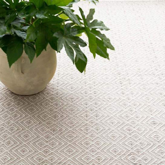 Annabelle Grey Indoor/Outdoor Rug styled with a vase and greenery. Styled view. 