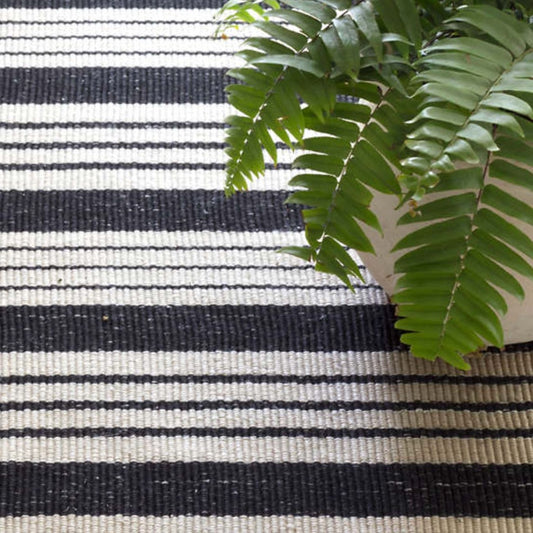 Birmingham Black Indoor/Outdoor Rug styled under a plant. Styled view. 