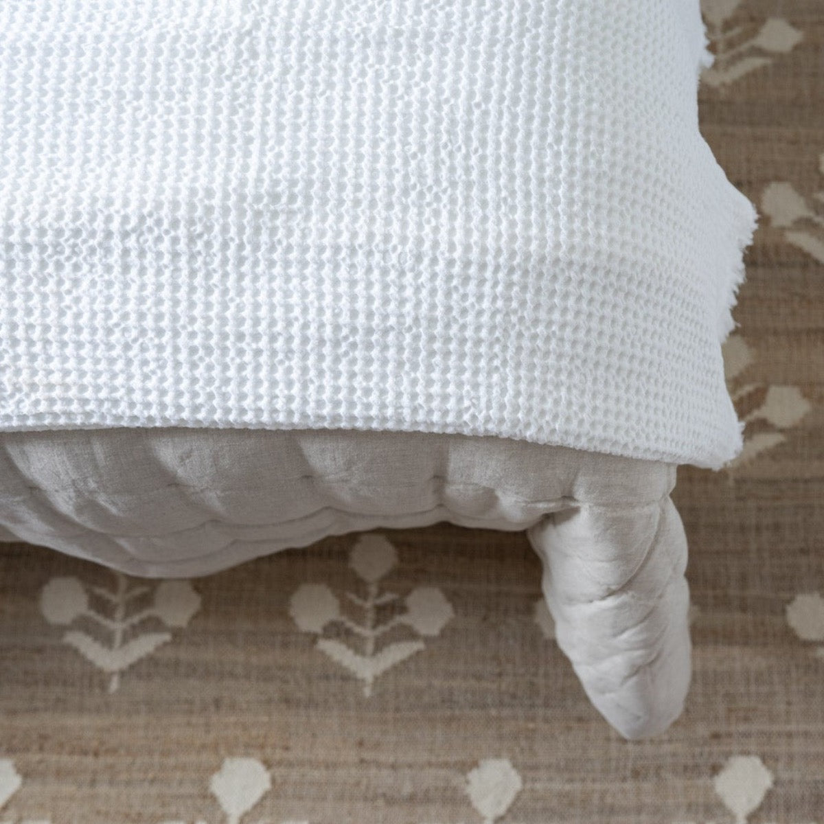 Bloom Jute Rug styled under bedding. Styled view. 