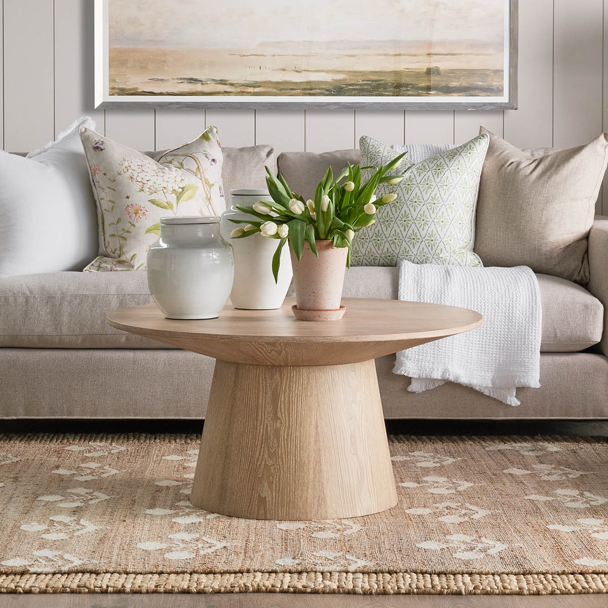 Bloom Jute Rug styled in a neutral living room with coffee table and sofa. Styled view. 