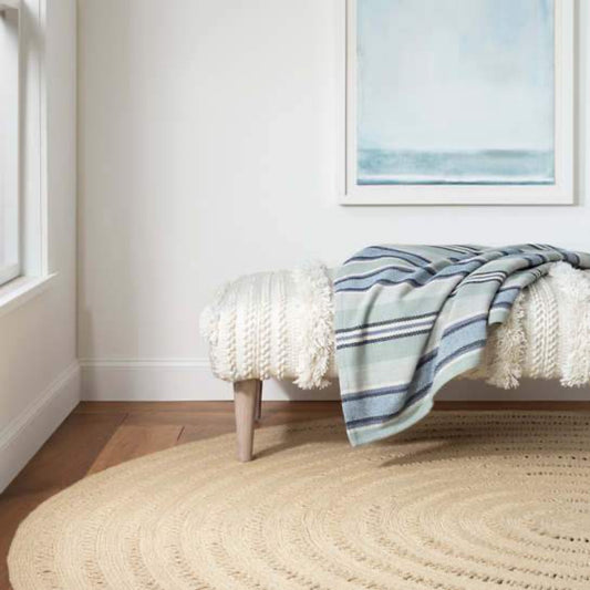Bowline Natural Indoor/Outdoor Round Rug styled with a bench in a white room. Styled view. 