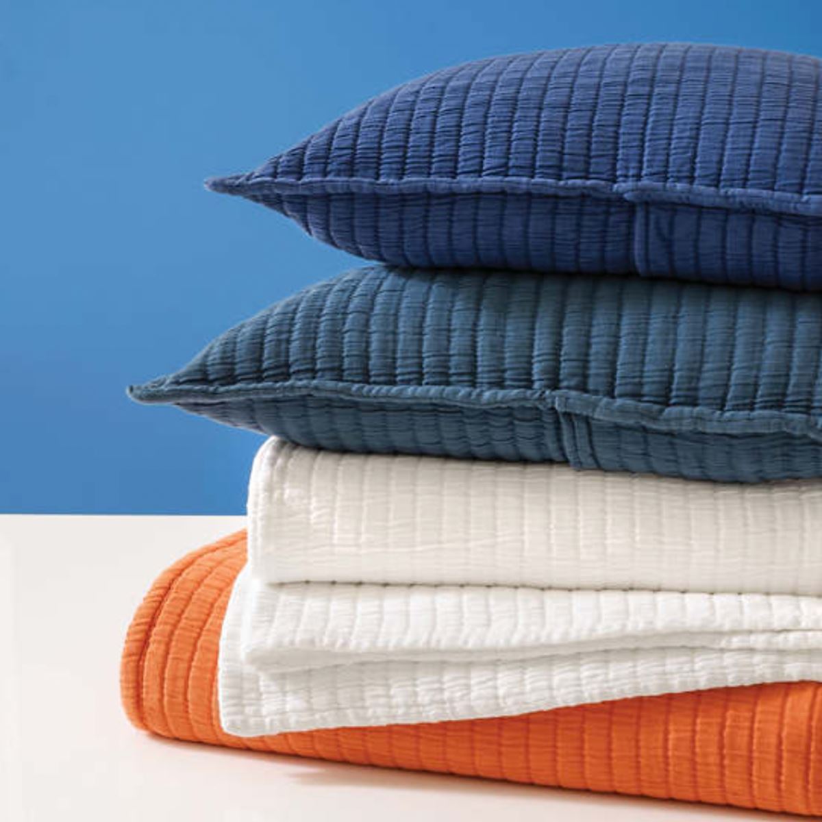 Stack of folded coverlets and pillows. Styled view.