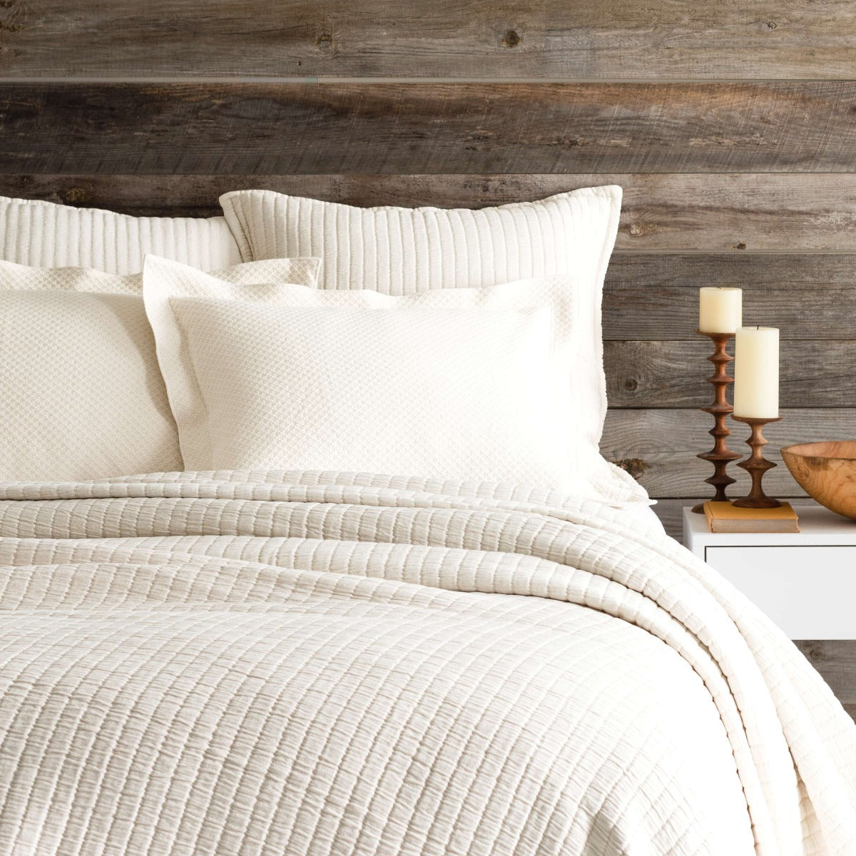 Boyfriend Ivory matelasse coverlet styled against a wood wall. Styled view. 