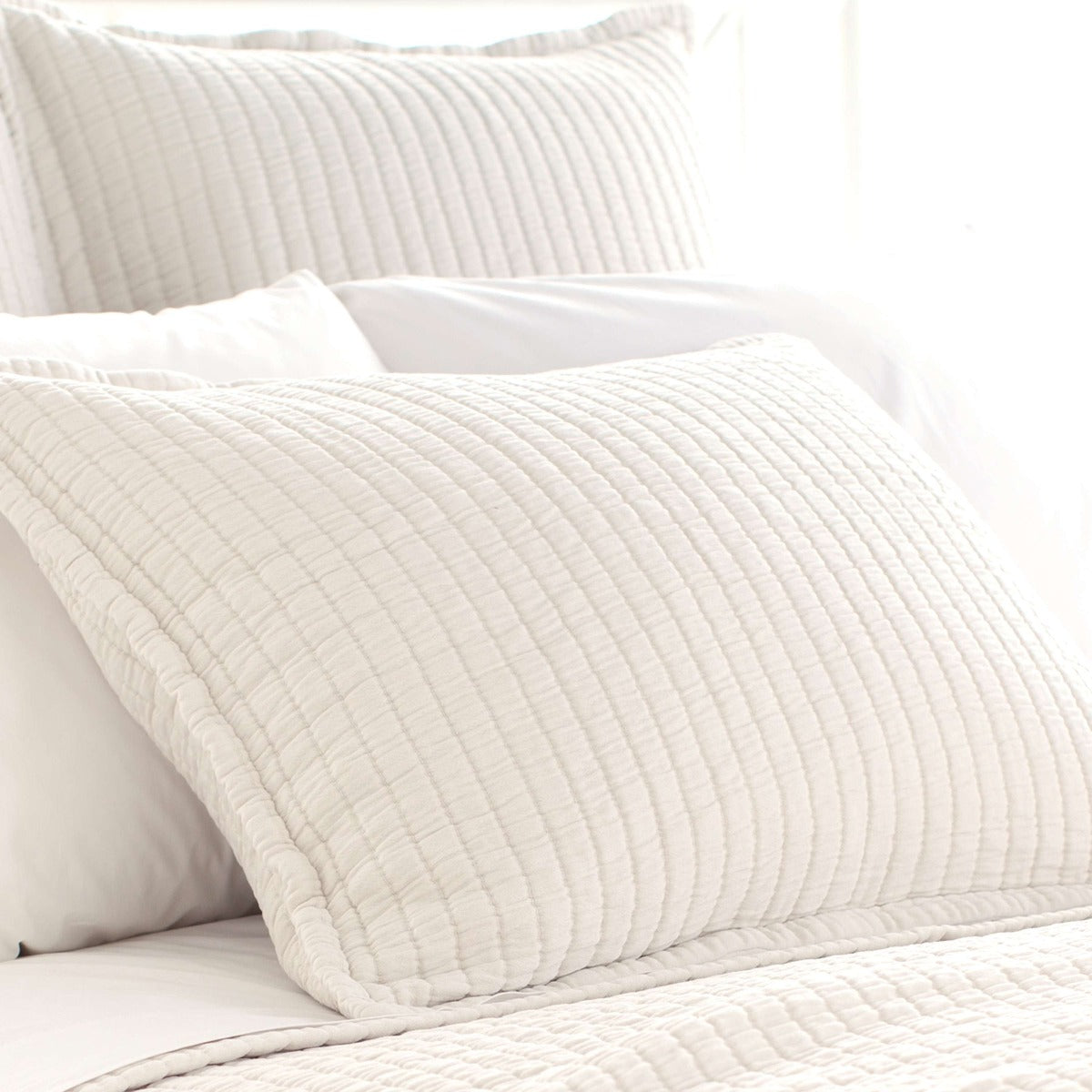 Boyfriend Ivory matelasse sham styled with white sheets. Styled view. 