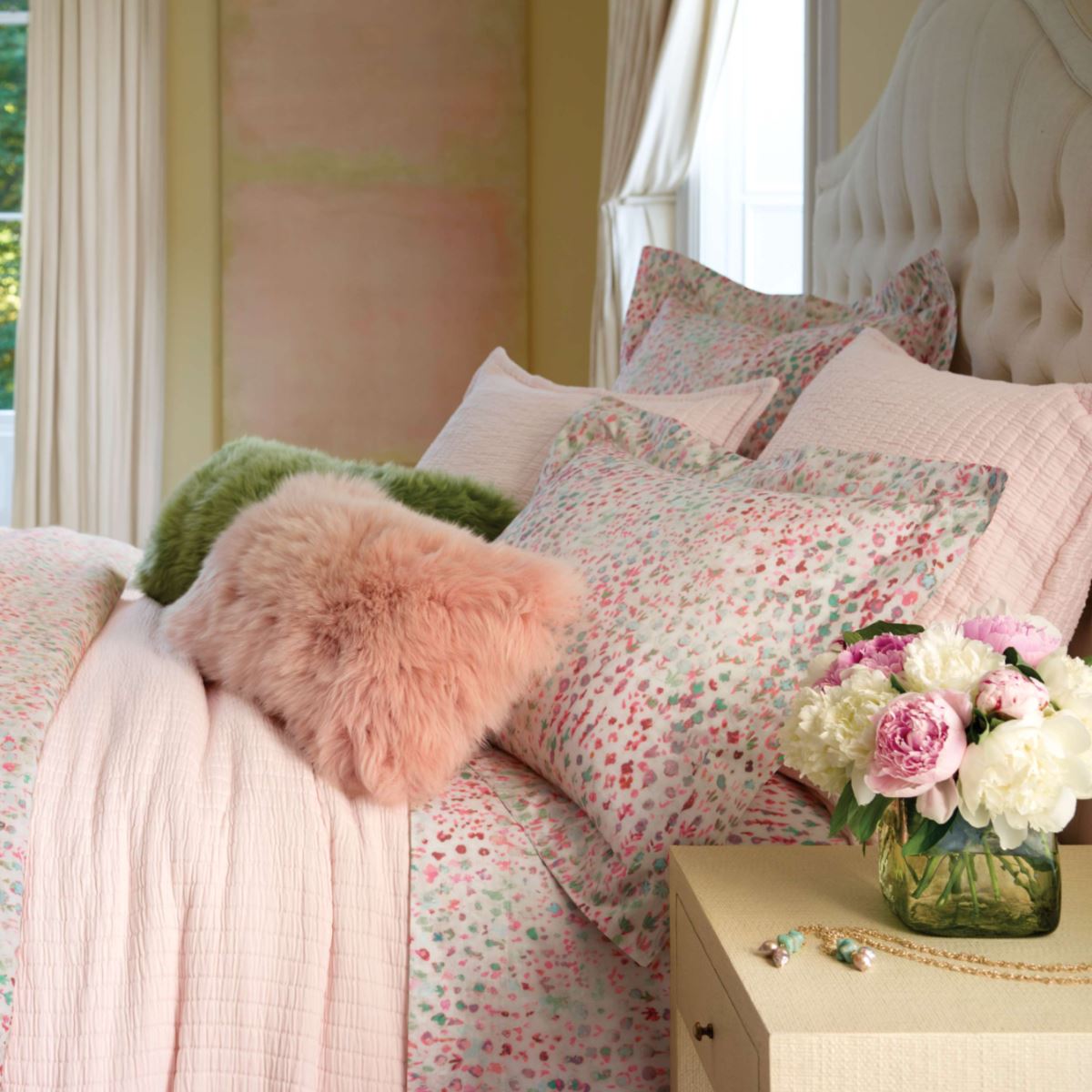 Pink and turquoise spotted bedding with light pink coverlet and pink and green pillows. Styled view.