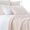 Light pink textured bedding styled with white sheets. Styled view.