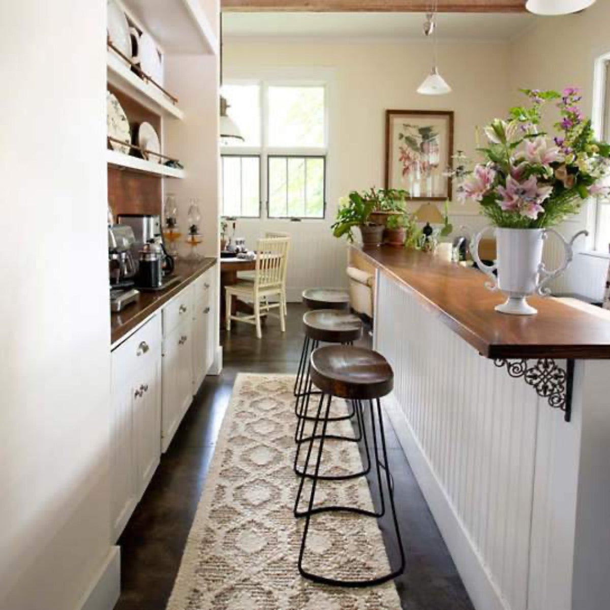 Capri Soumak Woven Jute Rug styled under barstools in a kitchen. Styled view. 