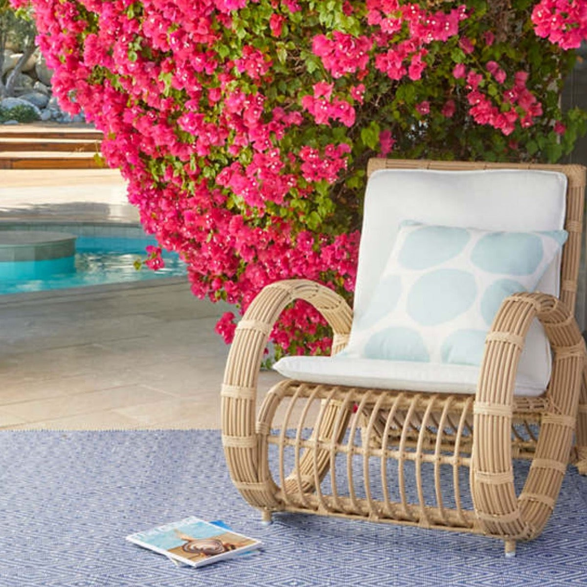 Diamond Denim/White Indoor/Outdoor Rug styled outdoors with a wicker chair and pink florals. Styled view. 