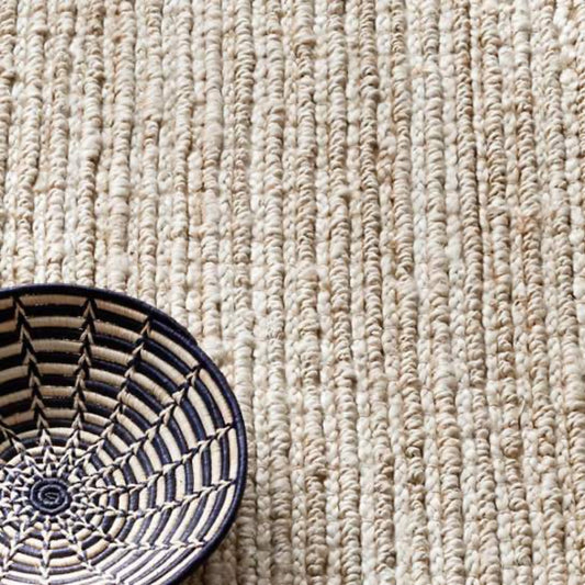 Dunes Bleached Oak Woven Jute Rug styled with a blue bowl. Styled view. 