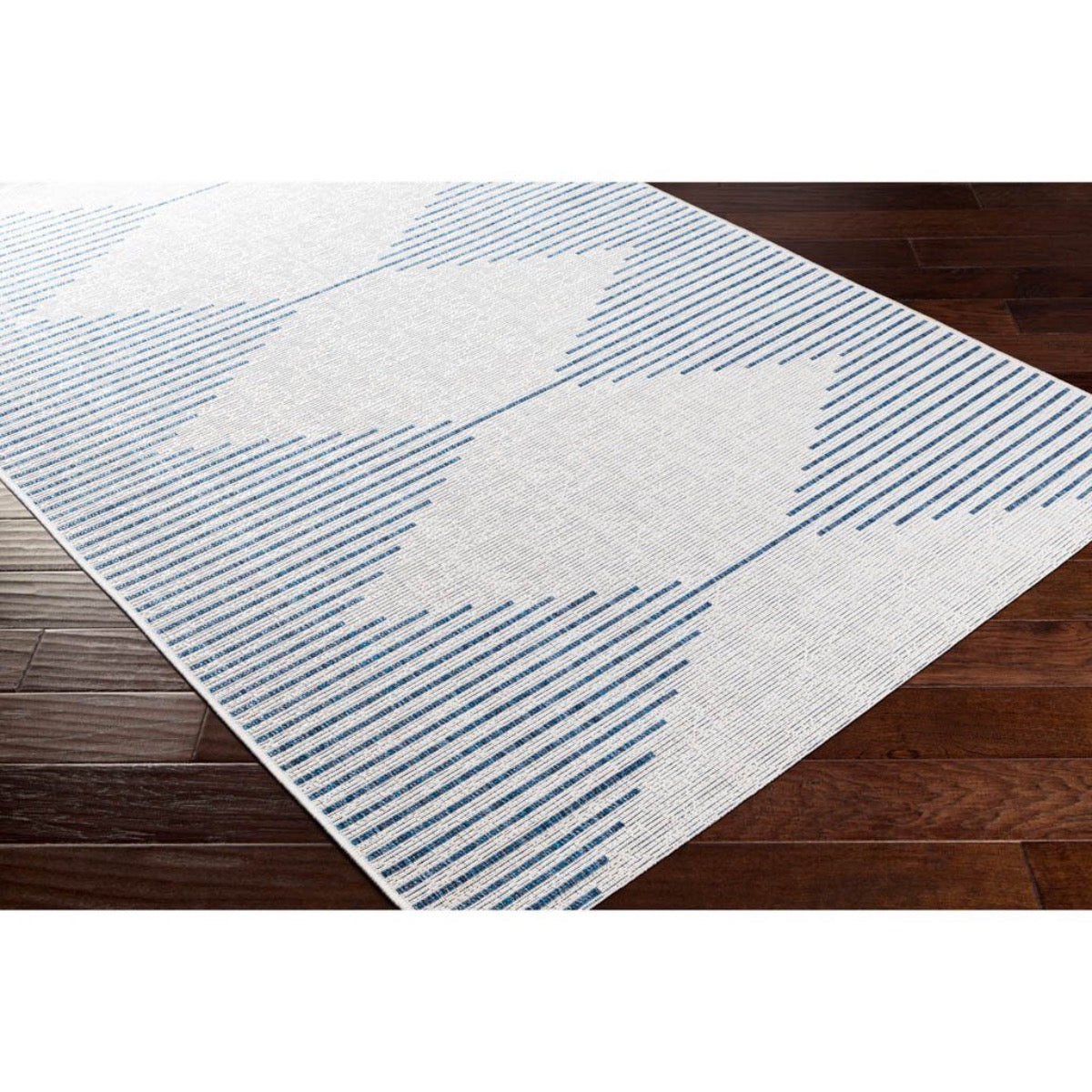Egan Outdoor Rug styled over dark wood floor. Styled view. 