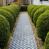 Elizabeth Navy Indoor/Outdoor Rugs styled outdoors down a pathway with shrubbery. Styled view. 