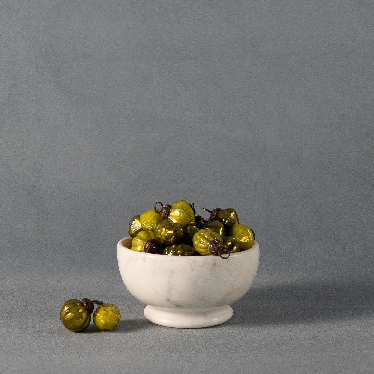 Footed Marble Bowl - Small Marble styled with green ornaments on grey. Styled view. 