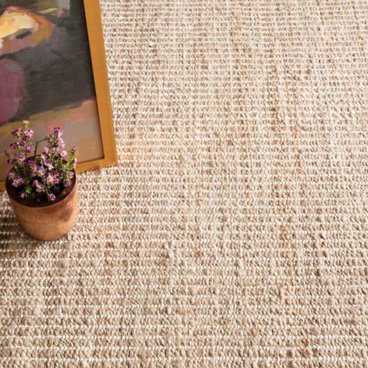 Gridwork Ivory Woven Jute Rug styled under frames and pots. Styled view. 