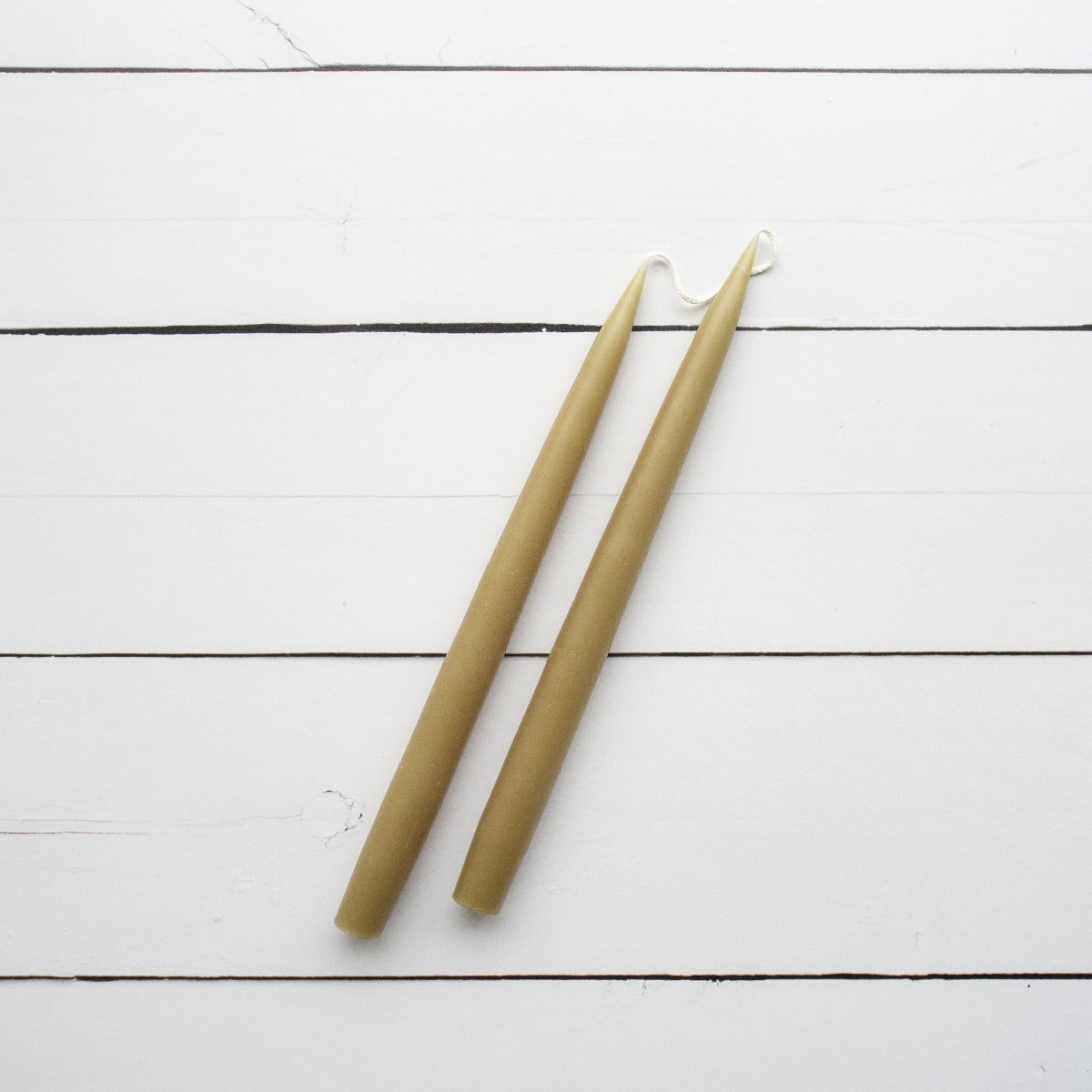 Hand-Dipped Danish Tapers - Olive styled against white wood. Styled view. 