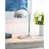 Harwich Desk Lamp styled on a wood console with books and greenery. Styled view.