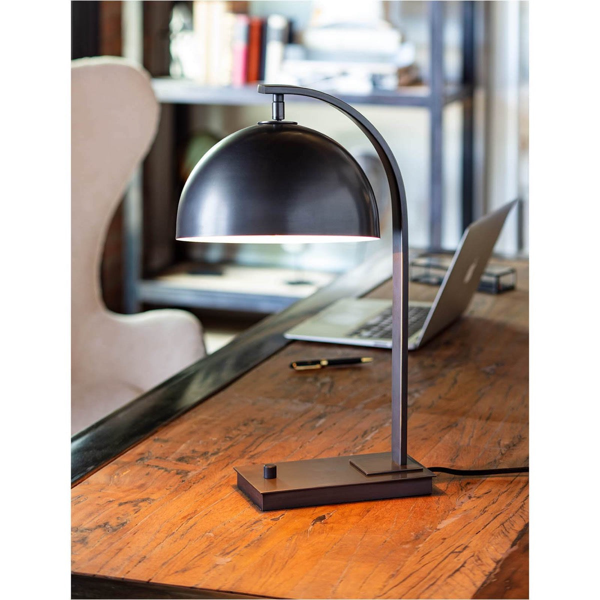 Harwich Desk Lamp styled on a wood desk on an office space. Styled view.