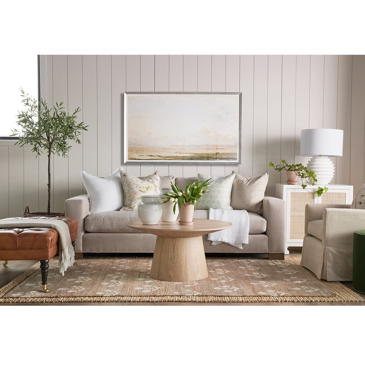 Henry Sofa styled in a white room with leather ottoman and spring decor. Styled view. 