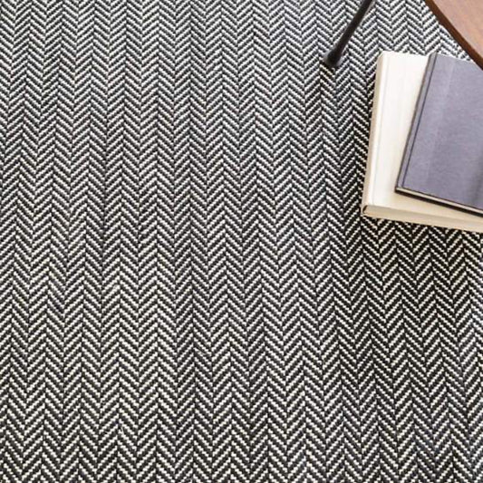 Herringbone Black Woven Cotton Rug styled under books. Styled view. 