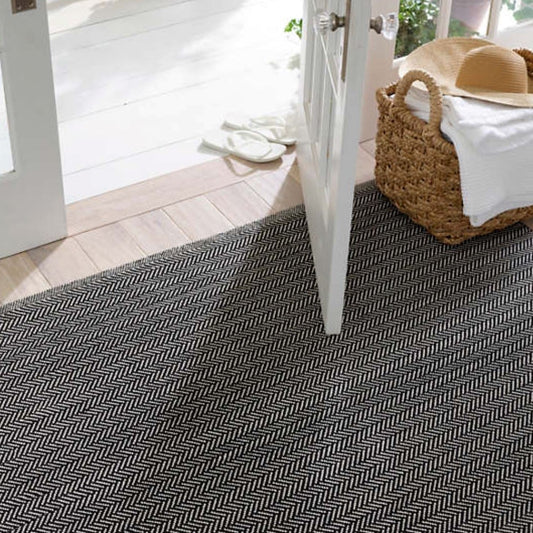 Herringbone Black/Ivory Indoor/Outdoor Rug styled in an entryway with white accents. Styled view.