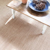 Herringbone Stone Woven Cotton Rug styled under a wood table. Styled view. 