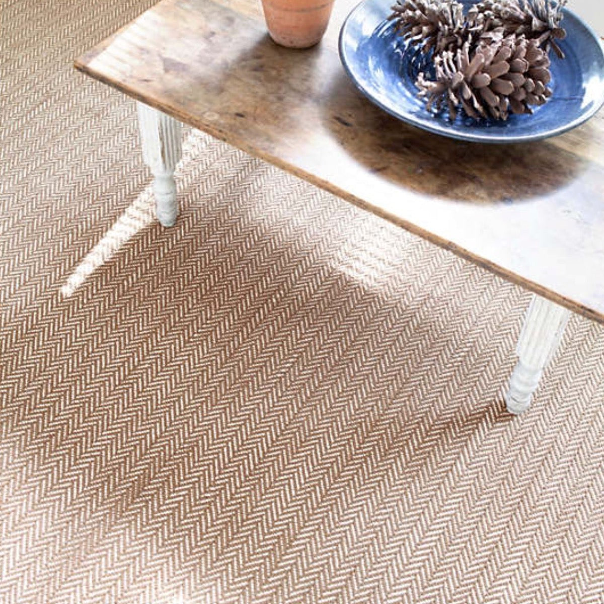 Herringbone Stone Woven Cotton Rug styled under a wood table. Styled view. 