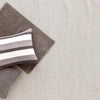 Honeycomb Ivory/Grey Woven Wool Rug styled under grey pillows. Styled view.