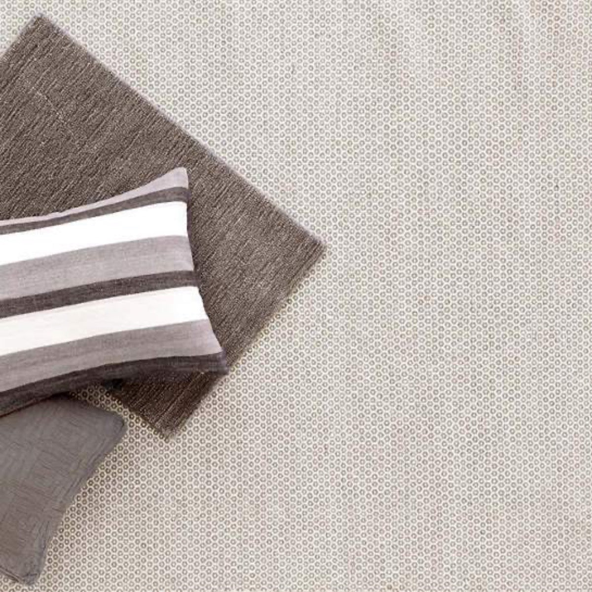 Honeycomb Ivory/Grey Woven Wool Rug styled under grey pillows. Styled view.